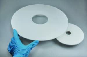 Eine Hand in einem Handschuh hält eine weisse Platte