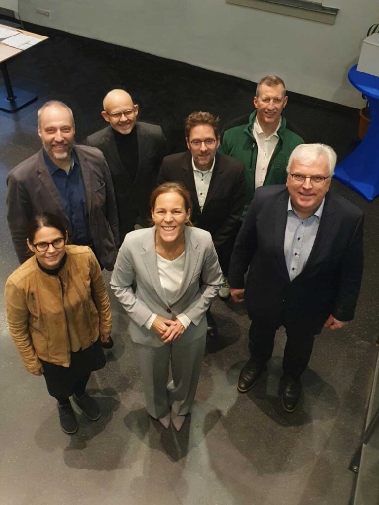 Sieben Menschen blicken von unten in die Kamera
